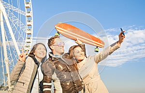 Young hipster people trio taking selfie at luna park ferris whee