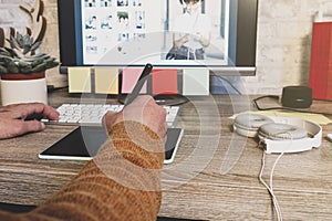 Young hipster photographer using digital graphic tablet while working in modern office, professional retoucher sitting at modern