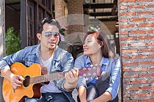 Young hipster practiced guitar in the park,happy and enjoy playing guitar. photo