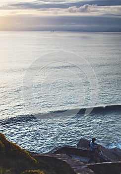 Young hipster relax on the beach on background ocean sunrise, silhouette romantic person looking view evening seascape, girl enjoy