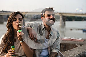 Young hipster stylish vintage couple enjoying life, sitting near the river, spending nice and fun time together. Freedom and