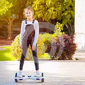 Young hipster teenager girl balancing on electric Hover Board, Dual Wheel Self Balancing Electric Skateboard sunny park.