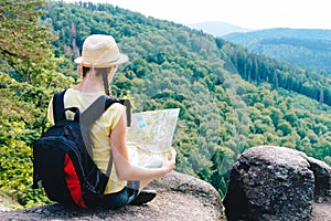 Young hipster tourist girl holding and looking map on trip