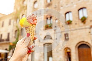 Hipster traveler eating ice-cream in old Italian town