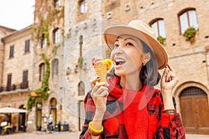 Hipster traveler eating ice-cream in old Italian town