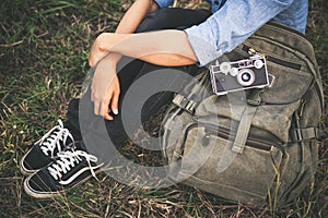Young hipster traveller woman with backpack sitting in the grass