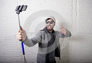 Young hipster trendy blogger man holding stick recording selfie video in vlog concept