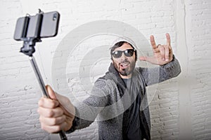 Young hipster trendy blogger man holding stick recording selfie video in vlog concept photo