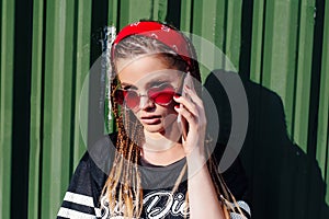 Young hipster woman with bandana and braids talking on the phonesmart on sunny summer day outdoor photo