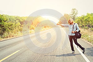 Young hipster woman hitchhiking on countryside road wait for the