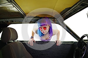 Young hipster woman looking in old rusty car isolated