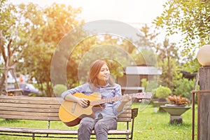 Close up of young hipster woman practiced guitar in the park,happy and enjoy playing guitar photo