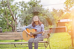 Close up of young hipster woman practiced guitar in the park,happy and enjoy playing guitar photo