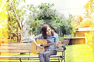 Close up of young hipster woman practiced guitar in the park,happy and enjoy playing guitar photo