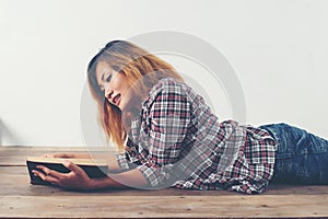 Young hipster woman reading book lay down on wooden floor at home.