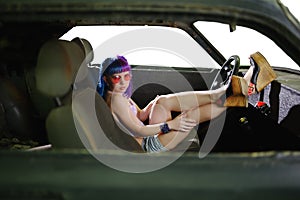 Young hipster woman sits in old rusty car