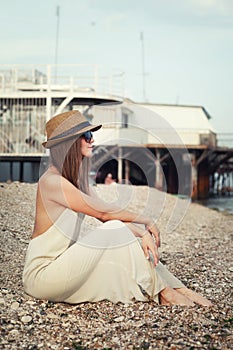 Young hipster woman sitting on a seacoast.