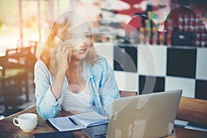 Young hipster woman talking phone and working at coffee shop.