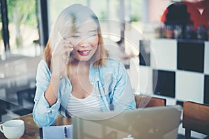 Young hipster woman talking phone and working at coffee shop.