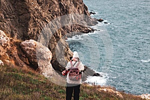 A young hipster woman walks on the rocks near the sea. Winter travel to coastal countries. Crimea, Balaclava