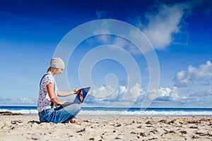 Young hipster woman working on laptop at the beach