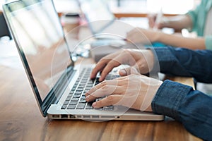 Young hipster worker typing on laptop keyboard in office