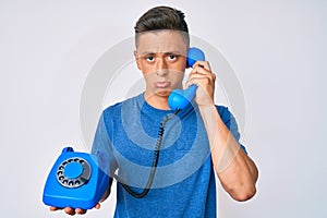 Young hispanic boy holding vintage telephone depressed and worry for distress, crying angry and afraid