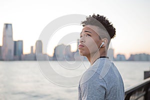 Young hispanic boy listening to music while facing the river