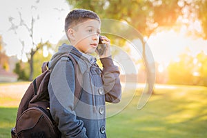 Young Hispanic Boy Walking Outdoors With Backpack Talking on Cell Phone