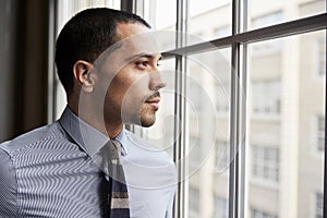 Young Hispanic business man looking out of window