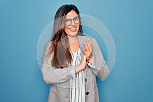 Young hispanic business woman wearing glasses standing over blue isolated background clapping and applauding happy and joyful,