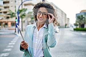 Young hispanic business woman wearing professional look smiling confident at the city holding worker clipboard