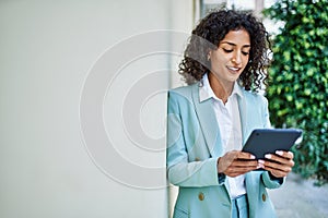 Young hispanic business woman wearing professional look smiling confident at the city using touchpad device