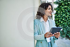 Young hispanic business woman wearing professional look smiling confident at the city using touchpad device