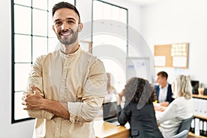 Young hispanic businessman smiling happy standing with arms crossed gesture at the office during business meeting