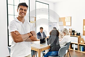 Young hispanic businessman smiling happy standing with arms crossed gesture at the office during business meeting