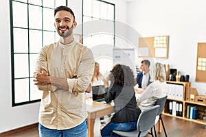 Young hispanic businessman smiling happy standing with arms crossed gesture at the office during business meeting