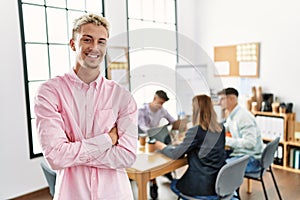 Young hispanic businessman smiling happy standing with arms crossed gesture at the office during business meeting