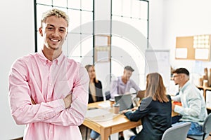 Young hispanic businessman smiling happy standing with arms crossed gesture at the office during business meeting