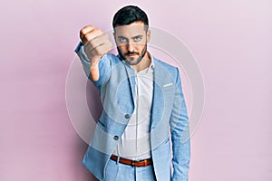 Young hispanic businessman wearing business jacket looking unhappy and angry showing rejection and negative with thumbs down