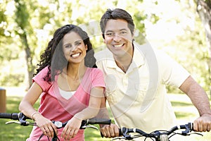 Young Hispanic Couple Cycling In Park