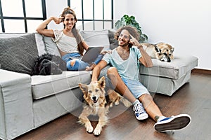 Young hispanic couple with dogs relaxing at home smiling pointing to head with one finger, great idea or thought, good memory