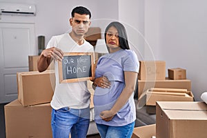 Young hispanic couple expecting a baby moving to a new home depressed and worry for distress, crying angry and afraid