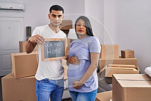 Young hispanic couple expecting a baby moving to a new home relaxed with serious expression on face