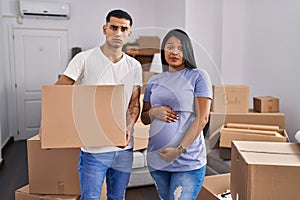 Young hispanic couple expecting a baby moving to a new home skeptic and nervous, frowning upset because of problem