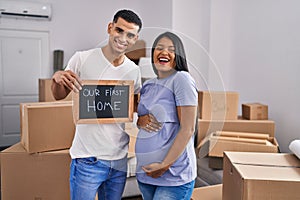 Young hispanic couple expecting a baby moving to a new home smiling and laughing hard out loud because funny crazy joke