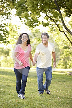 Young Hispanic Couple Running In Park