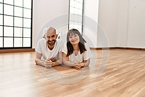 Young hispanic couple smiling happy lying on the floor at empty new home