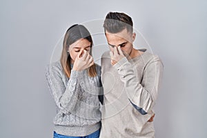 Young hispanic couple standing over white background tired rubbing nose and eyes feeling fatigue and headache