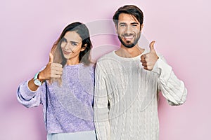 Young hispanic couple wearing casual clothes doing happy thumbs up gesture with hand